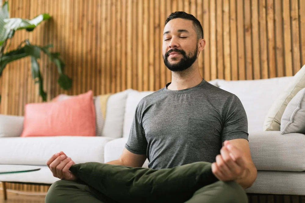 Hombre joven sentado en el suelo practicando meditación