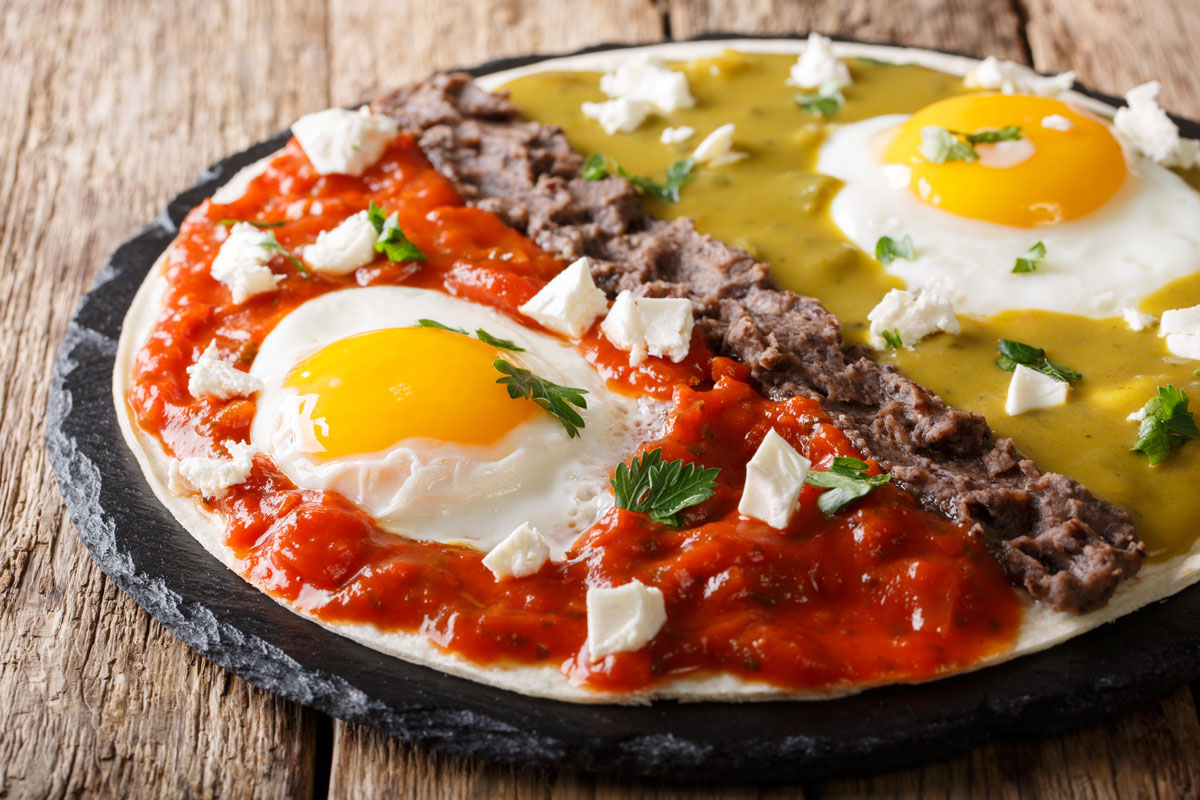 Platillo de huevos divorciados sobre una tortilla de harina con frijoles