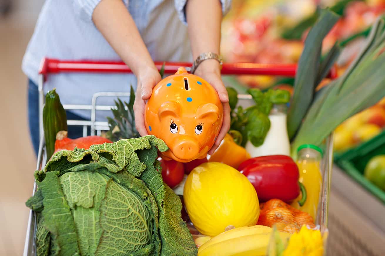 Una alcancía en un carrito de compras lleno de verduras
